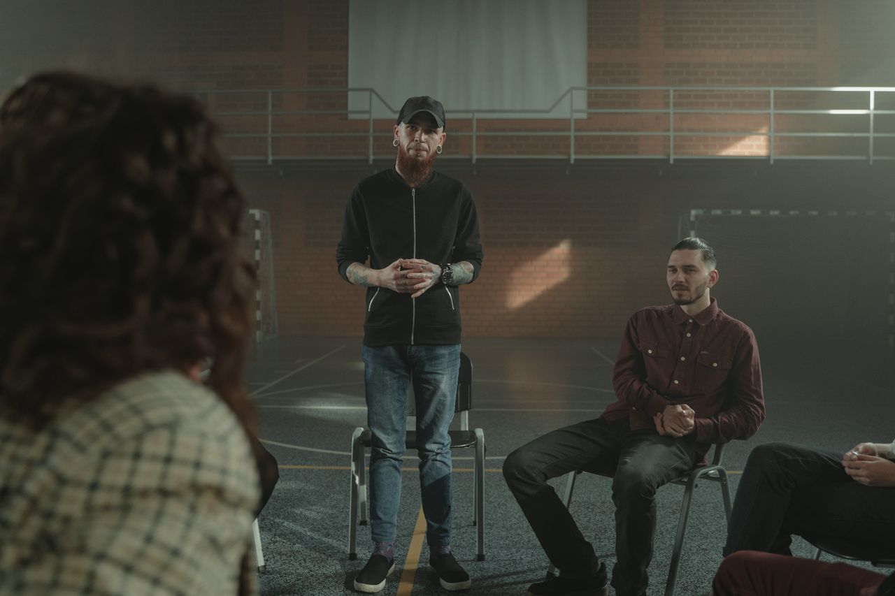 A group therapy session taking place indoors with diverse participants seated in a circle.